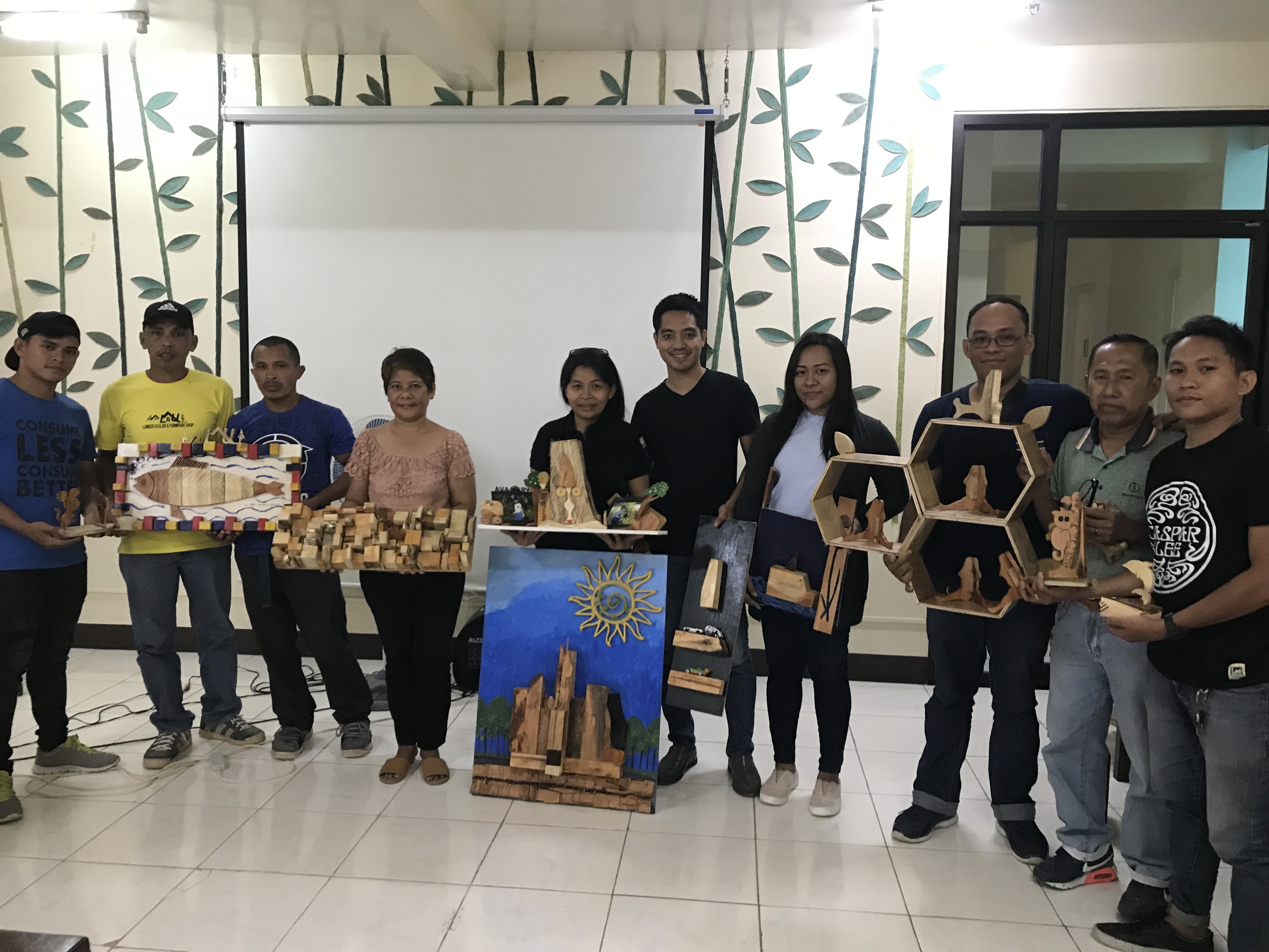 Training participants pose with their finished products, which include wall decors, table centerpieces, chair and frames