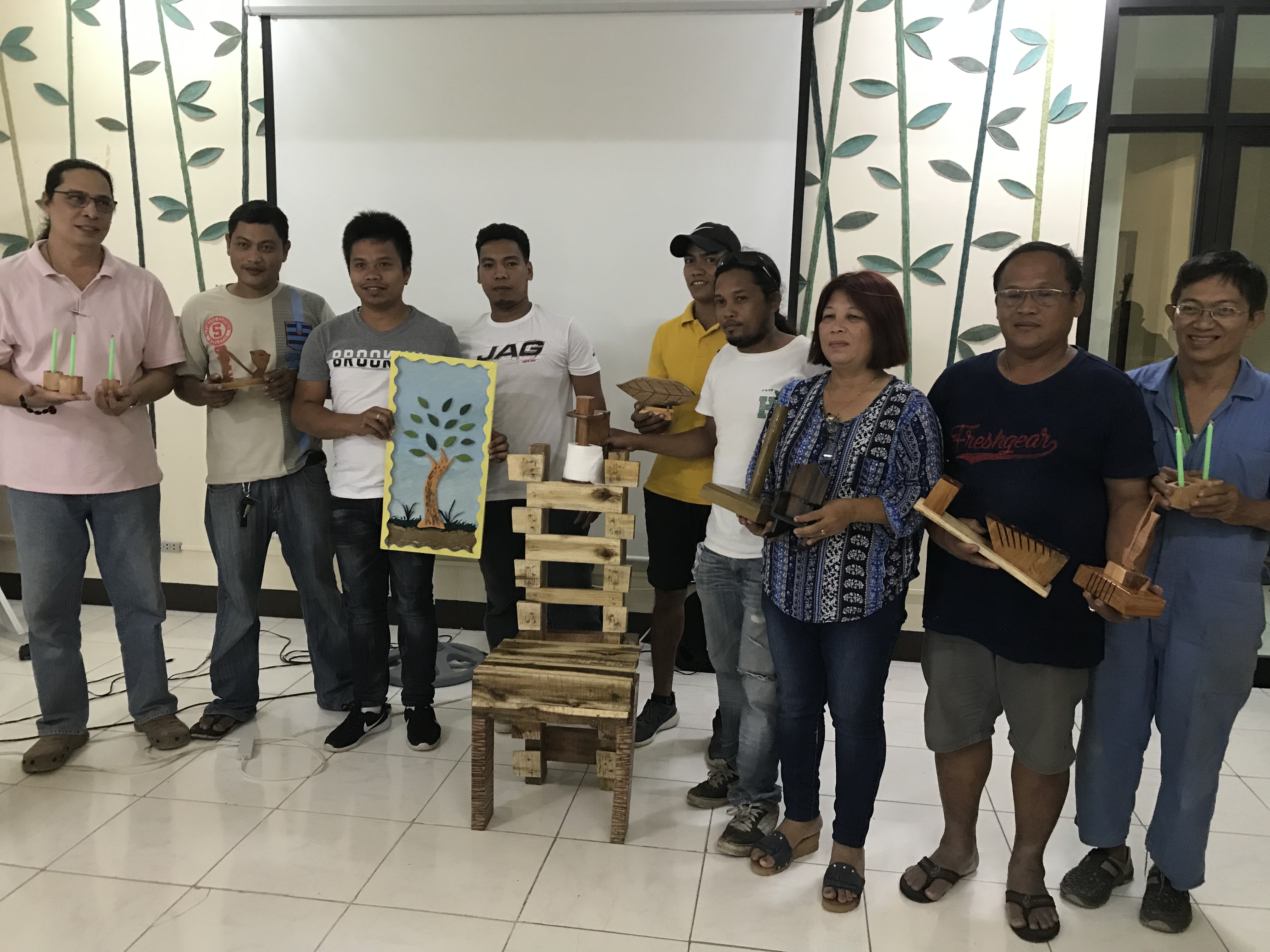 Training participants pose with their finished products, which include wall decors, table centerpieces, chair and frames